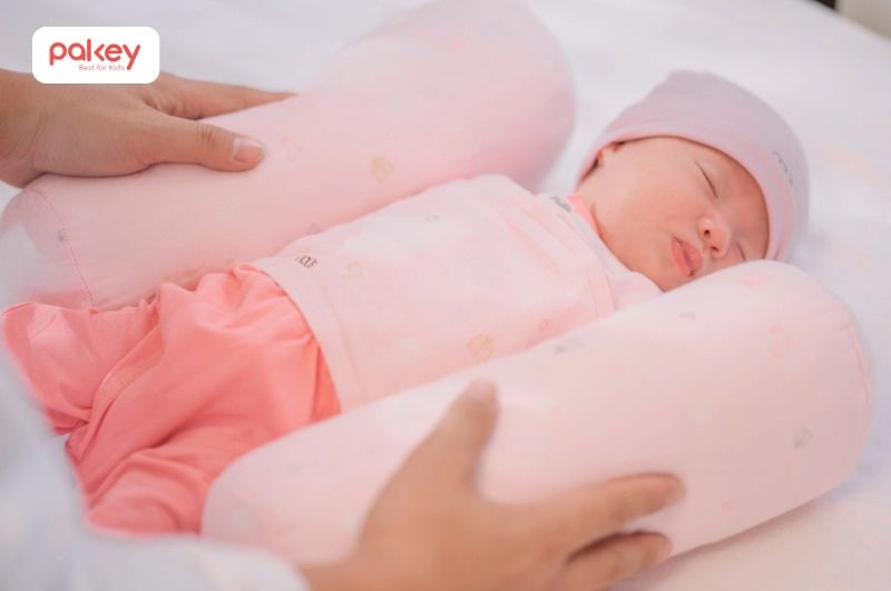 Việc sử dụng gối chặn hoặc gối bàn tay đặt hai bên cơ thể giúp trẻ có cảm giác được “ôm ấp”